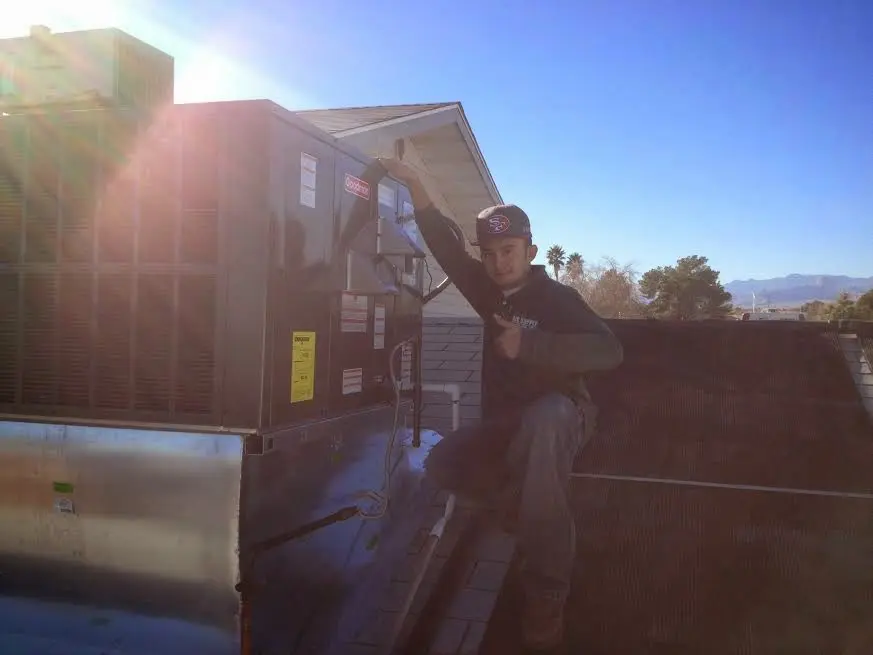 HVAC technician performing AC Tune-Up on a rooftop unit in Gulf Hills